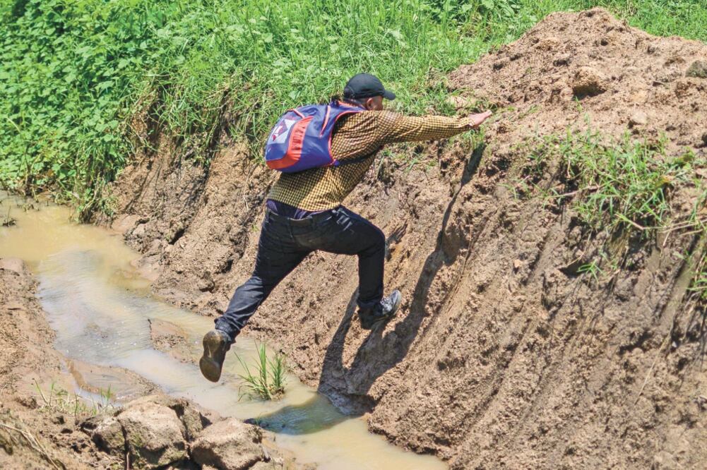 Un migrante guatemalteco cruza un riachuelo en su recorrido por una brecha para evitar a las autoridades migratorias en Chiapas. Foto/ PEDRO PARDO. AFP