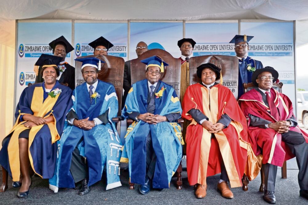 El presidente de Zimbabue, Robert Mugabe (centro), hizo ayer su primera aparición en público al presidir la ceremonia de graduación de universitarios cerca de la ciudad de Harare (BEN CURTIS. AP)