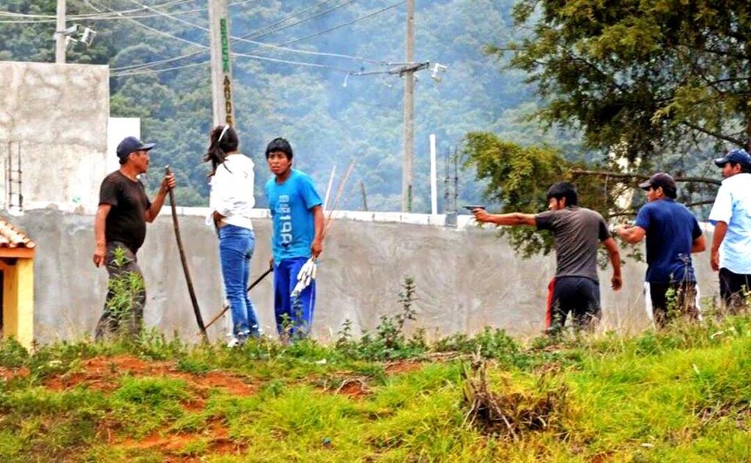 Cinco jóvenes indígenas detienen a una reportera que cubre el desalojo; uno de ellos le apunta con una pistola y le exige que entregue su cámara fotográfica (CORTESÍA TRAGAMELUZ)