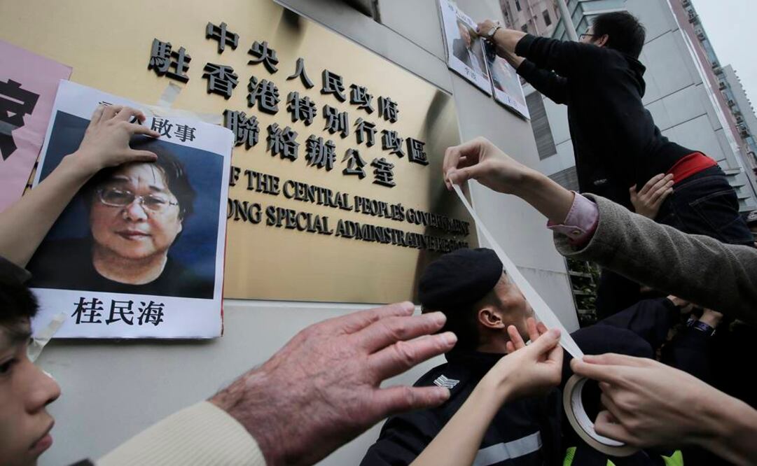 Manifestantes intentan colocar fotografías de los editores desaparecidos ante la oficina de Enlace del Gobierno Popular Central en Hong Kong. (Foto: AP / Vincent Yu)