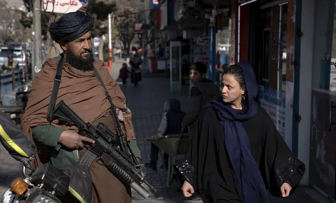 Un combatiente talibán monta guardia mientras una mujer pasa caminando en Kabul, Afganistán, el 26 de diciembre de 2022. Foto: AP
