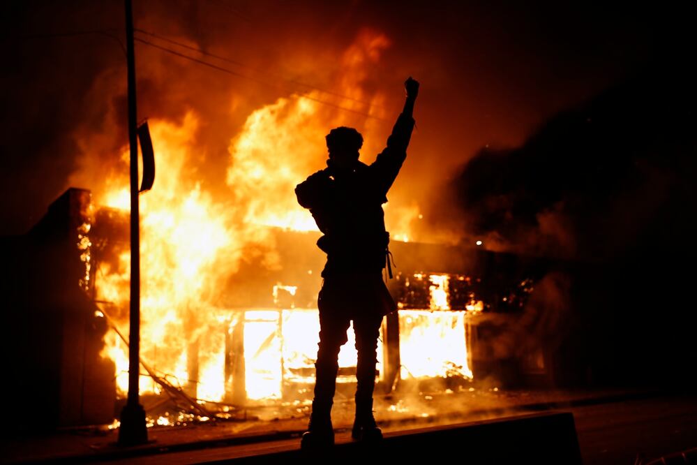 Un negocio de cambio de cheques arde durante las protestas en Minneapolis. FOTO: AP