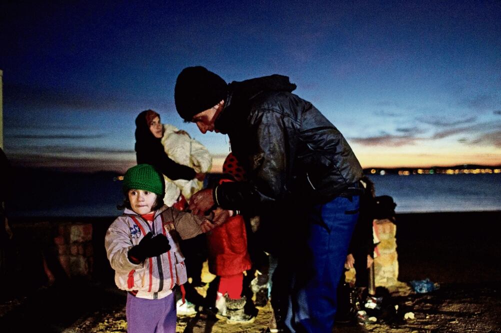 Un migrante afgano ayuda a su hija a ponerse los guantes a su llegada, el viernes, a la isla griega de Chios, tras un viaje difícil (PETROS GIANNAKOURIS. AP)