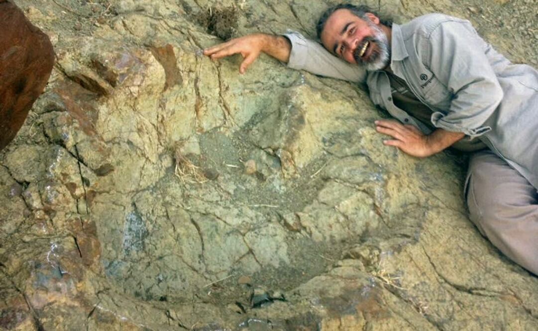 El paleontólogo argentino Sebastián Apesteguía posando  junto a la huella más grande de dinosaurios de este tipo en el mundo. FOTO: EFE