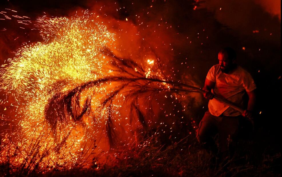 Un hombre intenta extinguir un incendio forestal con una rama de árbol en Trancoso, Portugal, el 12 de agosto de 2025. Foto: AFP