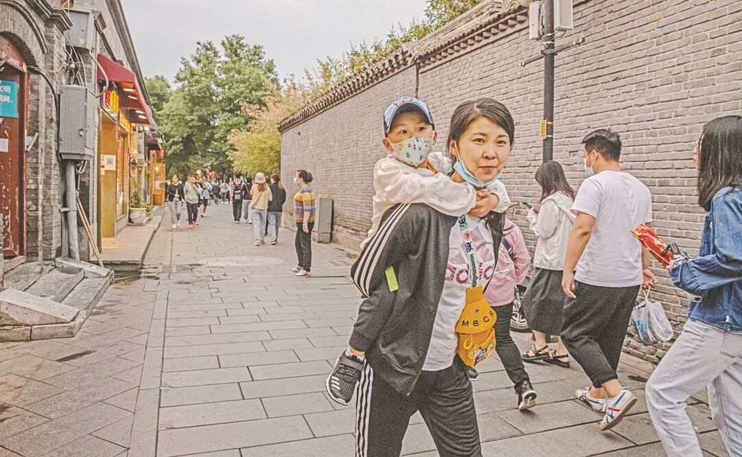 Una mujer carga a un pequeño, en un barrio de Beijing. El gobierno permitirá hasta tres hijos por familia. Foto: Roman Pilipey. EFE