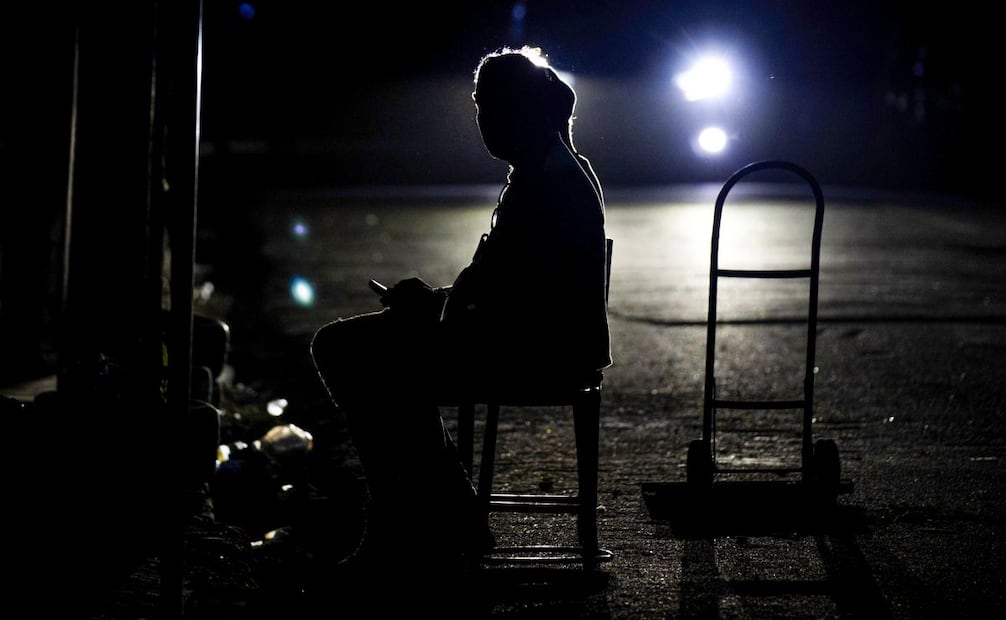 Una persona observa su teléfono móvil en una calle sin luz este lunes, en Santo Domingo (República Dominicana).El Gobierno dominicano afirmó que el sistema energético ha sido restablecido en un 30 %, tras el apagón general que se registró en horas de la mañana que trastocó el tráfico, así como labores educativas, de salud e industriales en el país. Foto: EFE