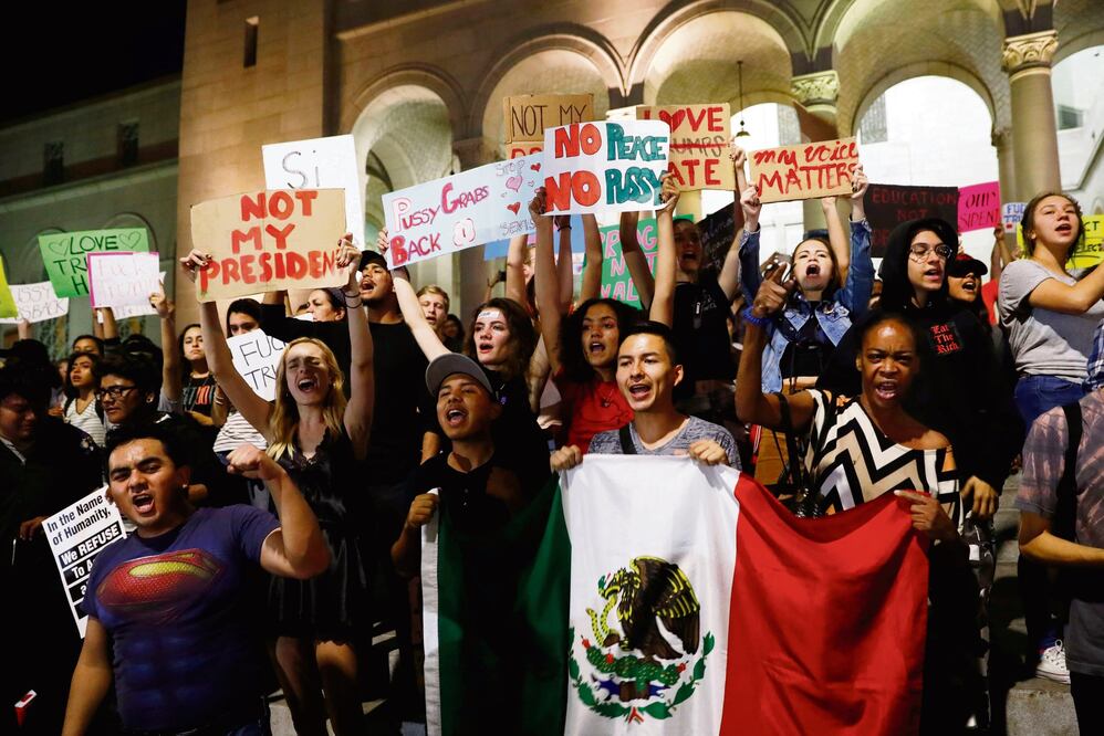 Manifestantes con la bandera mexicana y pancartas de “no al racismo”, durante una protesta contra Trump, el jueves, en Los Ángeles. (FOTO: PATRICK T. FALLON. REUTERS)