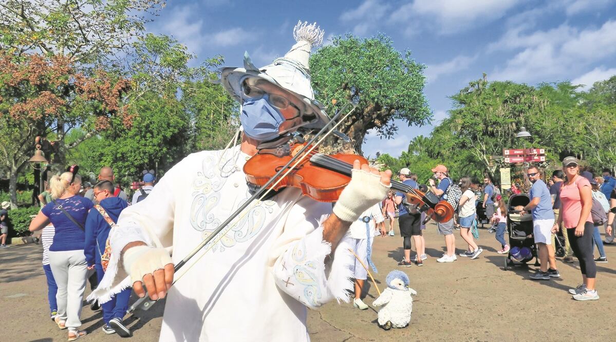 Un músico, protegido contra el Covid-19, alegra a los visitantes del Animal Kingdom en Florida. Los casos de Covid-19 en todo EU registran niveles récord por ómicron, aunque TImes Square, NY, se mantiene el festejo de Año Nuevo masivo para hoy. Foto:AP