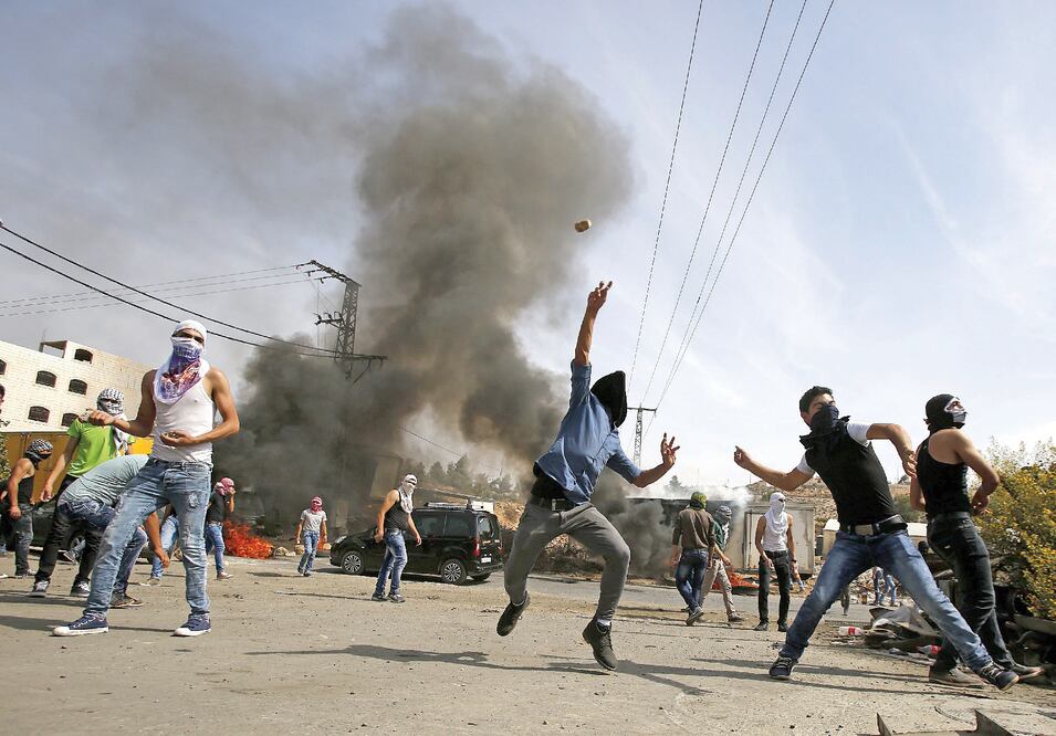 Palestinos arrojan piedras en choques con las fuerzas israelíes en Hebrón, el domingo (ESPECIAL)