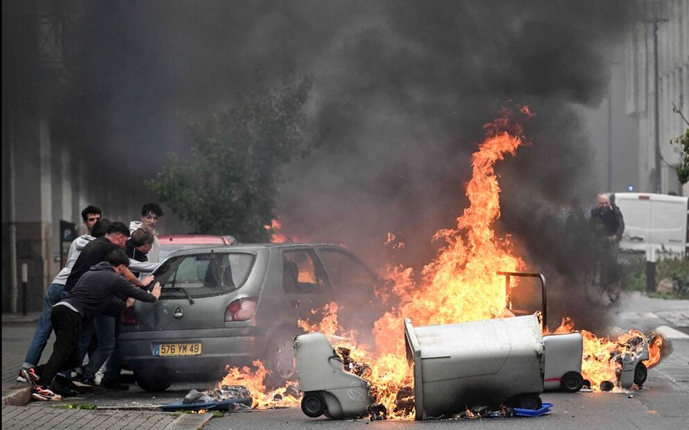 Residentes empujan un coche para evitar que se incendie con los contenedores de basura en la calle durante una manifestación del movimiento de protesta "Bloquons tout" ("Bloqueemos todo") en Nantes, Francia, el 10 de septiembre de 2025. Foto: AFP