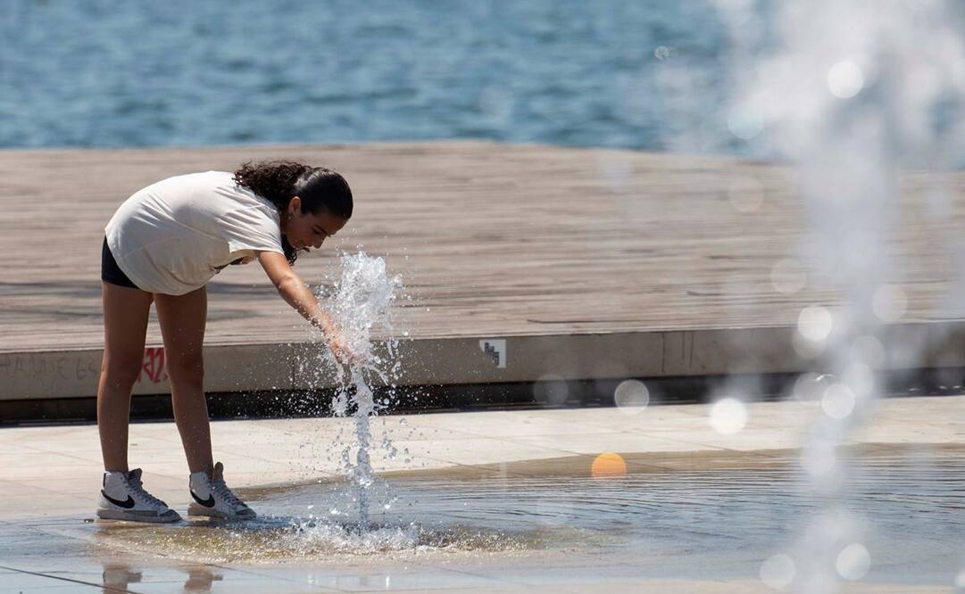 una turista se refresca en una fuente junto al mar en Salónica, Grecia. Foto: EFE