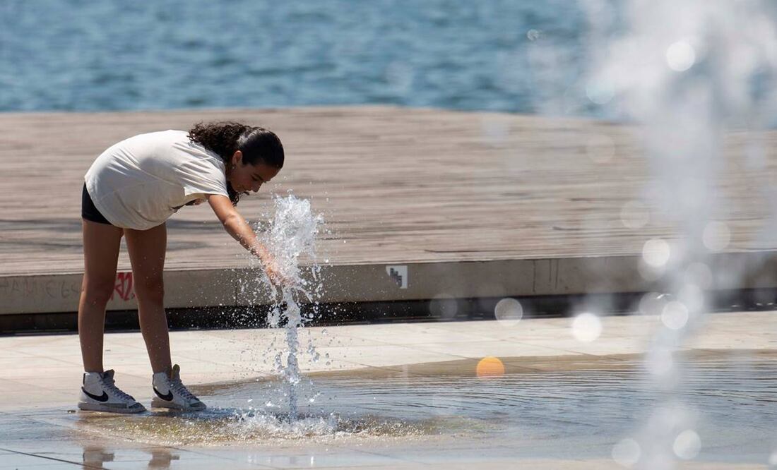 una turista se refresca en una fuente junto al mar en Salónica, Grecia. Foto: EFE