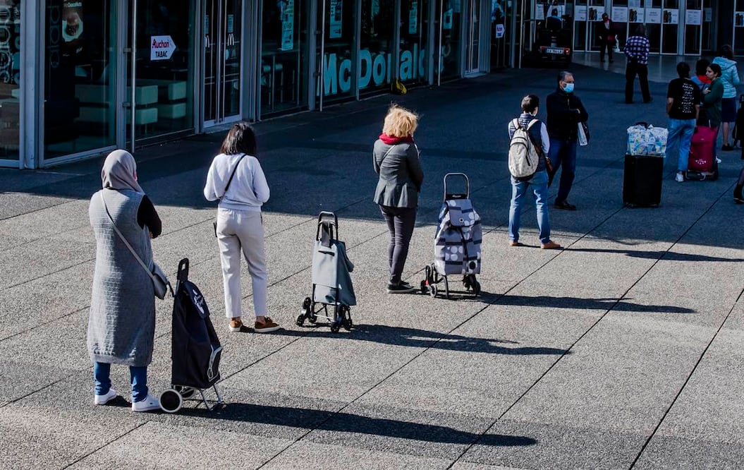 Personas usando cubrebocas hacen fila afuera de una tienda para comprar comida en La Defense, un distrito en París, Francia, en los días de la contingencia por la cuarentena. (AP Foto/Michel Euler)