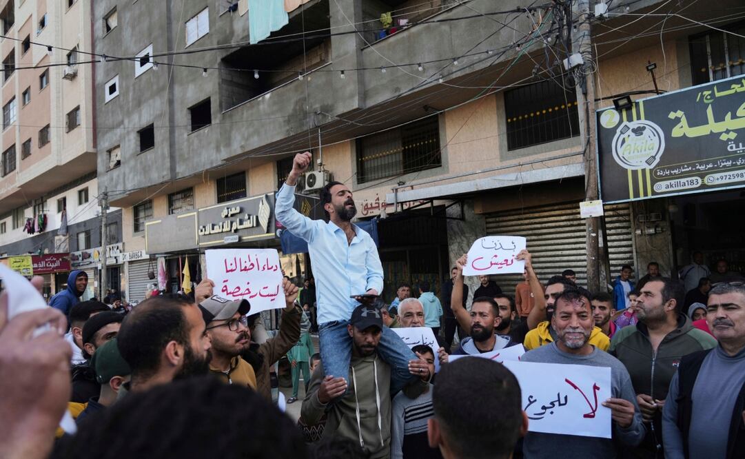 Palestinos sostienen carteles contra la guerra mientras un hombre canta consignas en apoyo a la gente de Bait Lahiya que se manifestó contra Hamas. Foto: AP