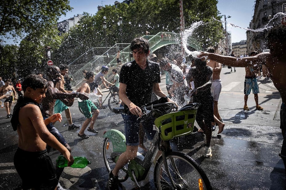 Adolescentes echan agua a ciclistas cerca del Canal de San Marttín, en París. FOTO: SIMON WOHLFAHRT. AFP