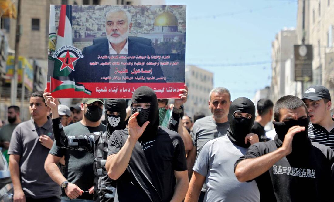 Hombres palestinos con una pancarta de la imagen del líder de Hamás, Ismail Haniyeh. Foto: AFP