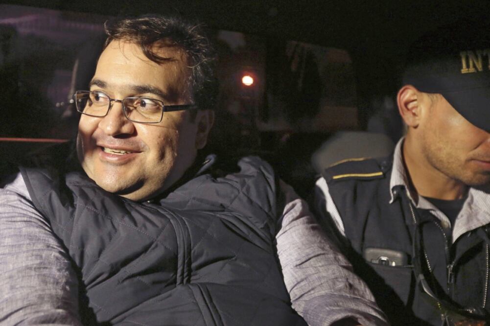 A la patrulla en la que fue trasladado curiosos se aproximaron para ver al detenido. Su sonrisa no desapareció, aun junto a los agentes. (ESTEBAN BIBA. EFE)