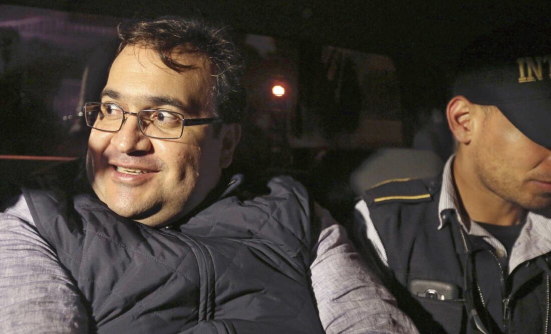 A la patrulla en la que fue trasladado curiosos se aproximaron para ver al detenido. Su sonrisa no desapareció, aun junto a los agentes. (ESTEBAN BIBA. EFE)