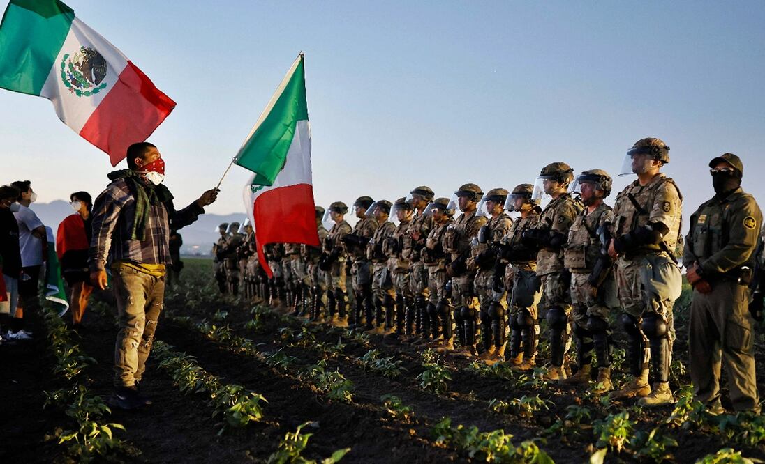 Personas con banderas de México se manifiestan frente a elementos de la Guardia Nacional durante una redada de inmigración del ICE en una granja de cannabis con licencia cerca de Camarillo, California, el 10 de julio de 2025. Foto: AFP