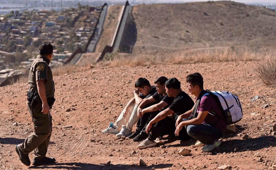 Un agente fronterizo, junto a cuatro hombres detenidos en San Diego después de cruzar la zona limítrofe con México. (24/01/2025) Foto: Gregory Bull | AP