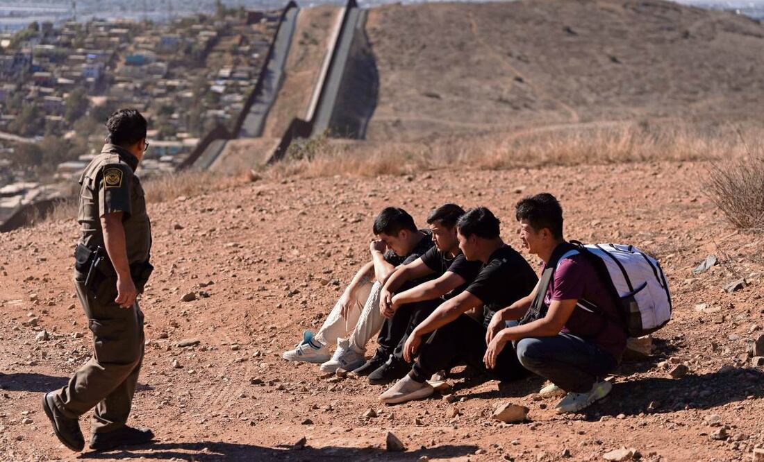 Un agente fronterizo, junto a cuatro hombres detenidos en San Diego después de cruzar la zona limítrofe con México. (24/01/2025) Foto: Gregory Bull | AP