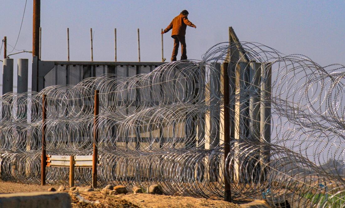 Una persona burla las alambradas de acero en Tijuana (Foto: EFE)