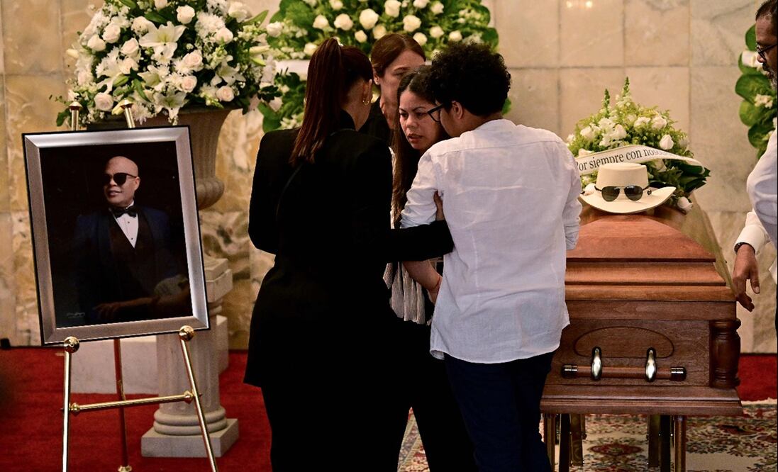 La hija de Rubby Pérez, Zulinka Pérez (C), y otros familiares junto al ataúd de su padre, quien falleció tras el derrumbe del techo de la discoteca Jet Set en donde se presentaba, en el Teatro Nacional de Santo Domingo, el 10 de abril de 2025. Foto: AFP