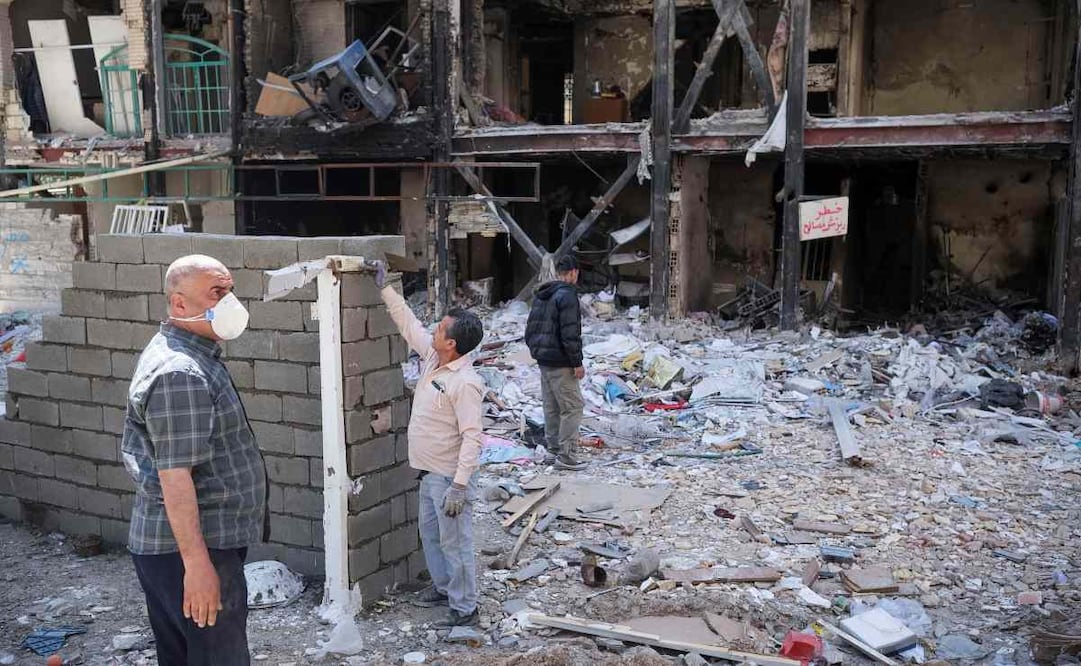Varios hombres trabajan en la construcción de un muro frente a un edificio destruido en el barrio de Boroujerdi, en el sureste de Teherán, que fue atacado en marzo por Estados Unidos e Israel. Foto: EFE