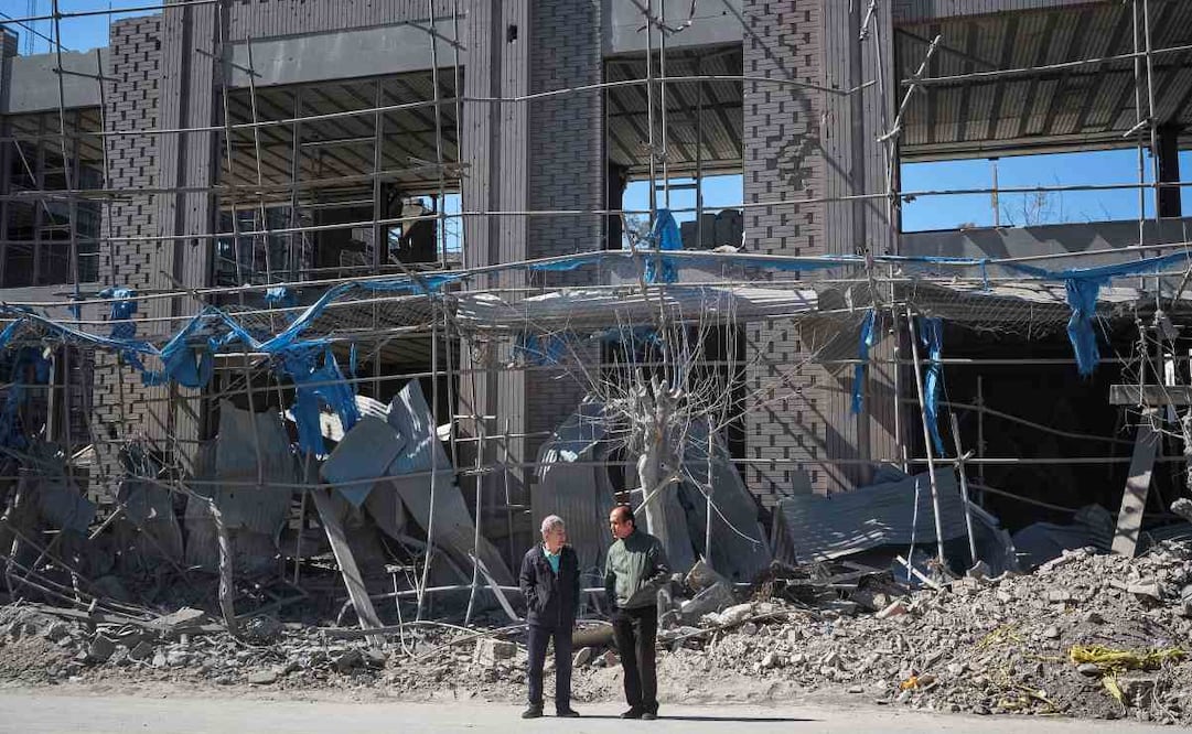 Dos personas caminan cerca de una zona alcanzada por los bombardeos israelíes-estadounidenses en Teherán. El Ejército israelí avisó de que atacará este martes la zona industrial Hakimiya en Teherán y el Aeropuerto Internacional de Payam en Karak, en el norte de Irán. Foto: EFE