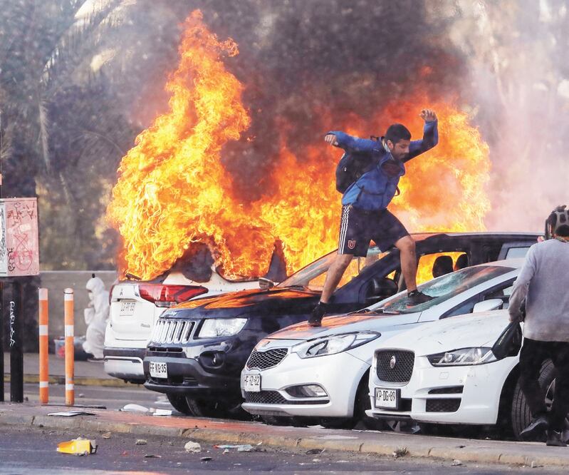 Un manifestante destruye un auto incendiado durante las protestas de ayer en el balneario Viña del Mar, donde arrancó el festival internacional más importante de Latinoamérica. Foto: LEANDRO TORCHIO. REUTERS