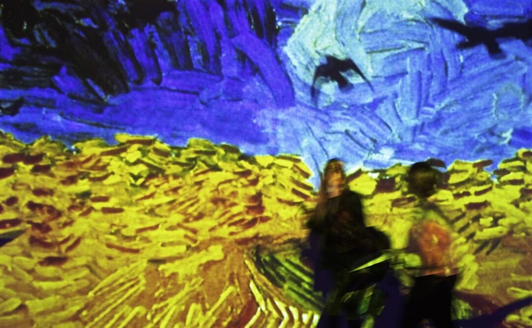 Dos mujeres caminan frente a la pintura "Campo de trigo con cuernos" de la exhibición "Van Gogh Alive" en Roma, Italia. Foto: Archivo