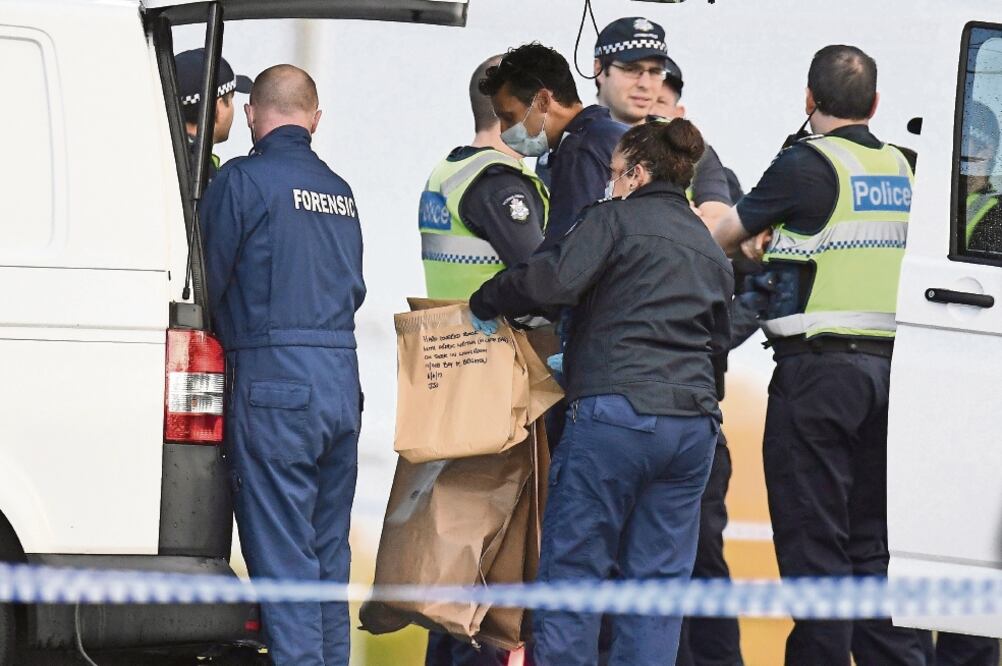 Elementos de la policía forense de Australia sostienen una bolsa con evidencia de la toma de rehén, en la cual se lee: “Libro de tapa dura con escritura árabe”. El incidente se registró ayer en Melbourne (JULIAN SMITH. REUTERS)