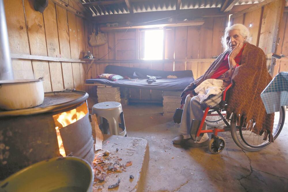 La abuela de la familia, de 90 años y en silla de ruedas, es colocada todas las mañanas por sus parientes frente a la estufa de leña por el frío. Fotos/JORGE ALVARADO. EL UNIVERSAL