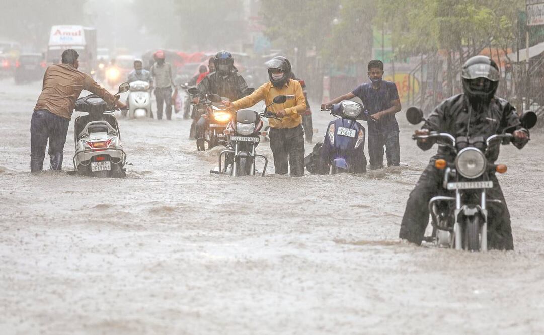 Ciudadanos pasan por una calle inundada, a causa de las lluvias que dejó el ciclón Tauktae en Gujarat. Foto: Divykant Solanki/ EFE.