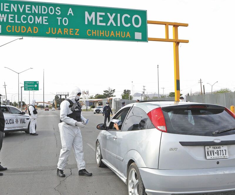 Agentes que se apostaron en el puente internacional Córdova-Américas vistieron trajes especiales para evitar el contagio de Covid-19 y entregaron volantes con información de las medidas sanitarias. HERIKA MARTÍNEZ. AFP