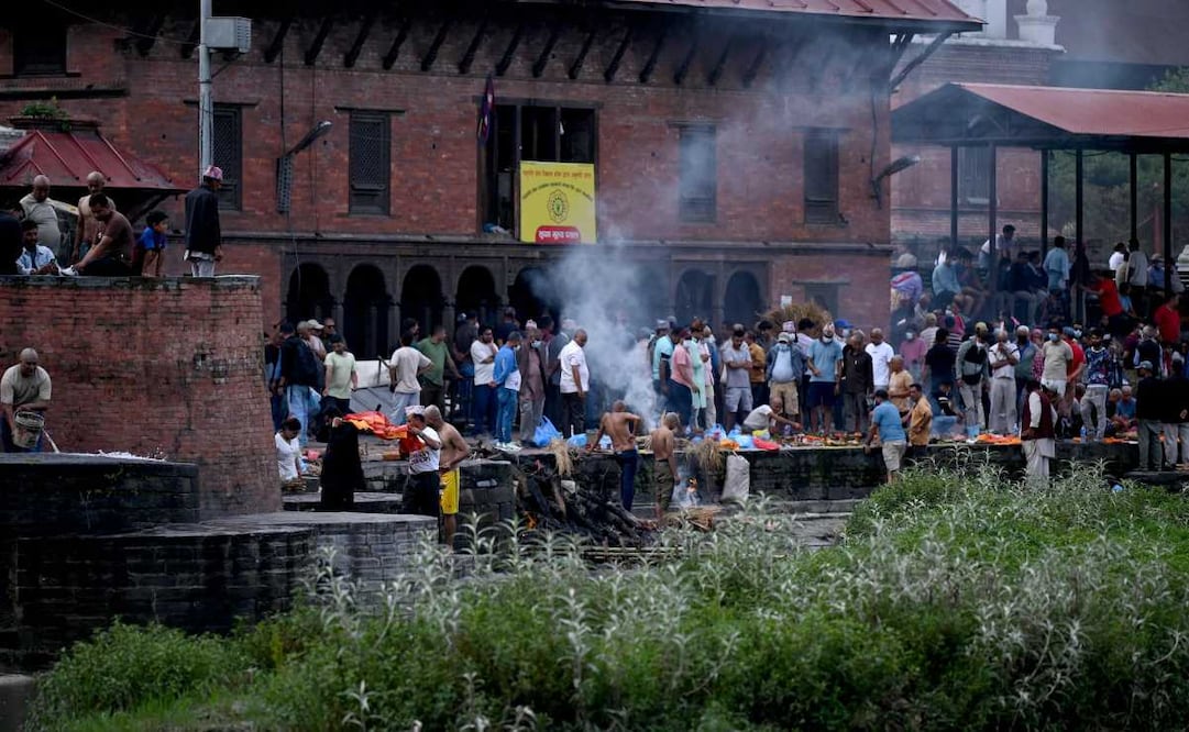 Familiares llevan a cabo ritos hindúes nepalíes para incinerar efigies hechas de hierba durante funerales simbólicos por las víctimas de la riada que permanecen desaparecidas, en el templo de Pashupatinath, Katmandú. Foto: AFP
