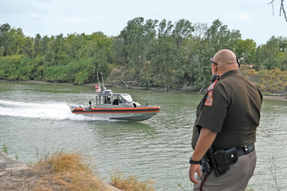 Una embarcación de la Guardia Costera estadounidense vigila el río Grande, mientras un oficial observa, cerca de Peñitas, en Texas. Foto: LOREN ELLIOTT. REUTERS