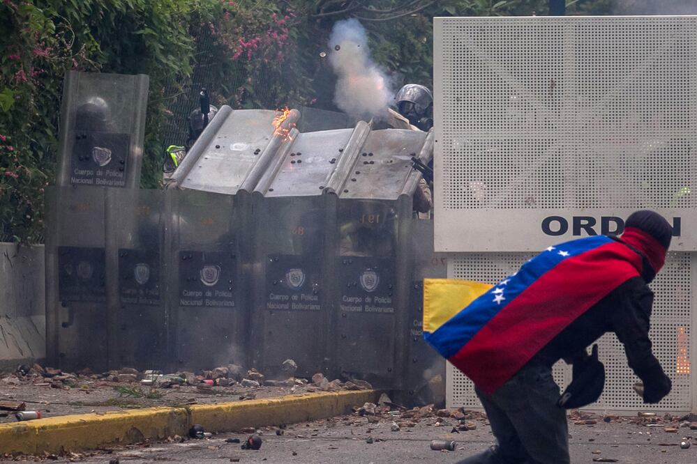 Manifestantes se enfrentan con policías antimotines en Caraca. Los cuerpos de seguridad dispersaron con gases lacrimógenos la manifestación de estudiantes. (EFE)