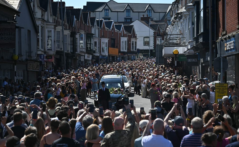 Personas en duelo y admiradores se alinean en las calles para presentar sus respetos mientras el coche fúnebre que transporta el féretro de la fallecida cantante Bonnie Tyler recorre su localidad natal de Mumbles, en el suroeste de Gales.
Foto de JUSTIN TALLIS / AFP.