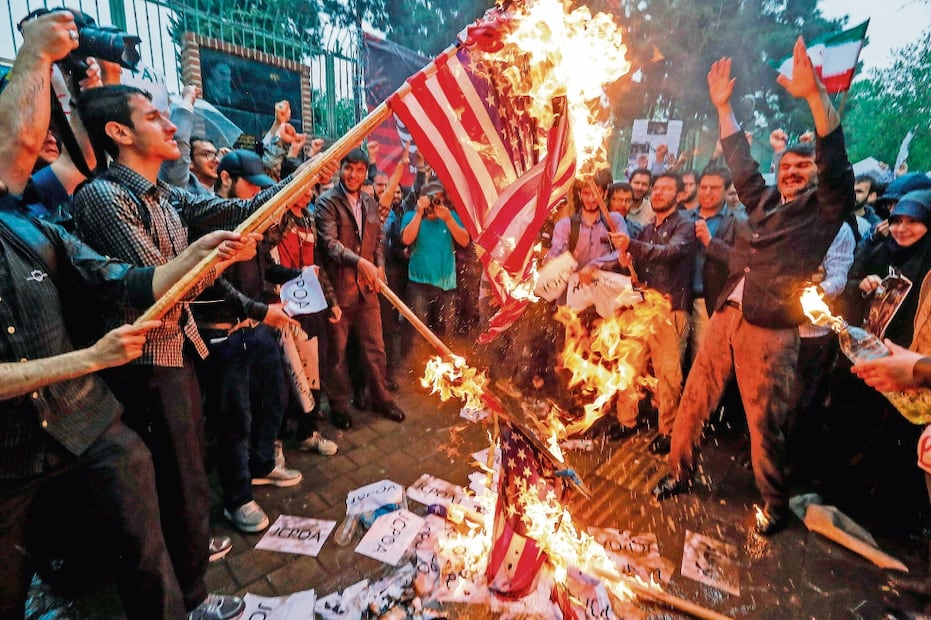 Iraníes prenden fuego a banderas estadounidenses, durante una protesta en Teherán por la decisión de Trump. Foto: ATTA KENARE. AFP