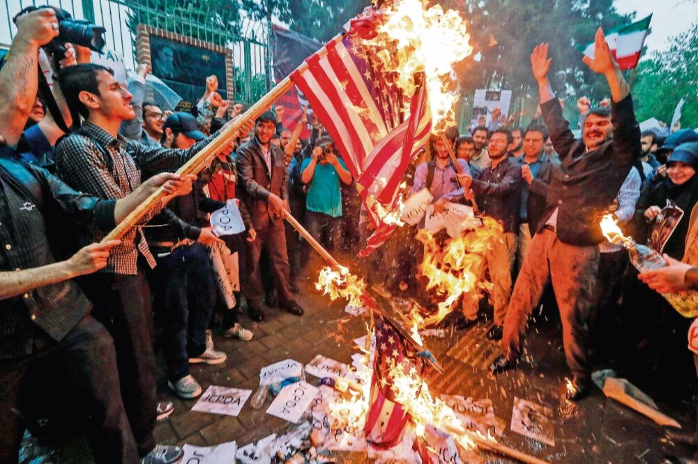 Iraníes prenden fuego a banderas estadounidenses, durante una protesta en Teherán por la decisión de Trump de abandonar el pacto nuclear de 2015 (ATTA KENARE. AFP)