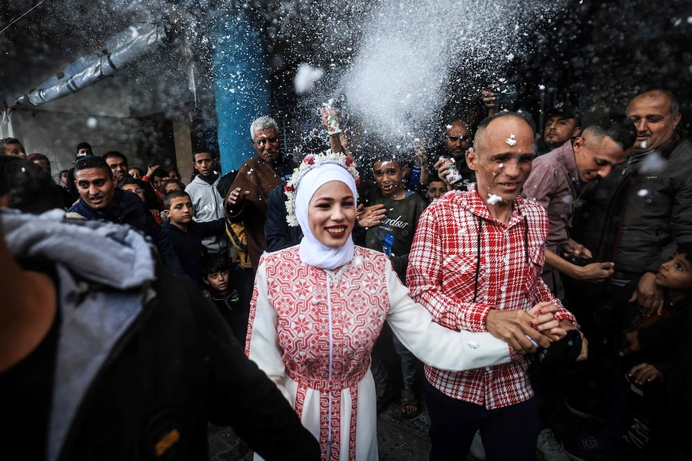 La novia palestina Afnan Yibril (centro) es acompañada por su padre (centro-derecha) durante su boda en la escuela de la UNRWA en el barrio de al-Salam de Rafah. Foto: AFP