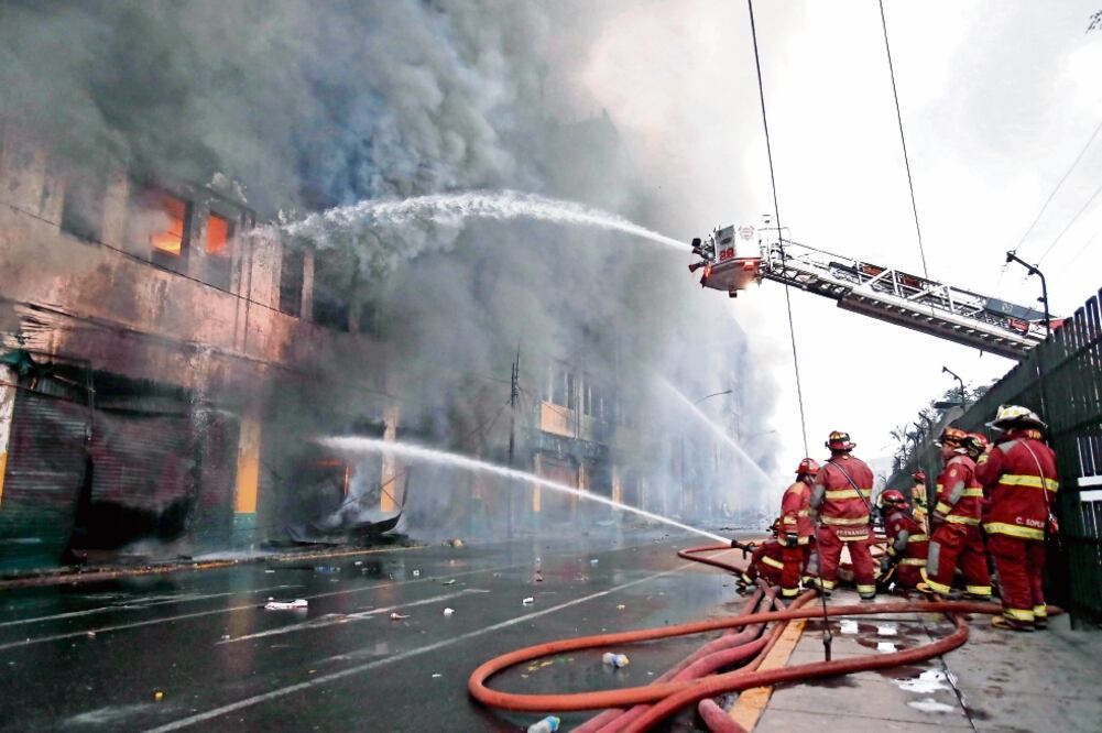 Bomberos intentaban apagar el incendio ocurrido en un edificio donde se venden productos de ferretería, en Lima; los trabajos durarán días, dijeron (JUAN COROMINAS. EFE)