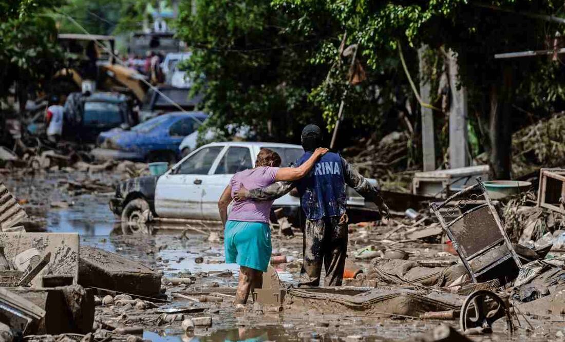 En Poza Rica, Veracruz, un elemento de la Marina ayuda a una mujer a cruzar la calle, que se encuentra cubierta de lodo, basura y escombros luego del desbordamiento del río. Foto: Félix Márquez / AP