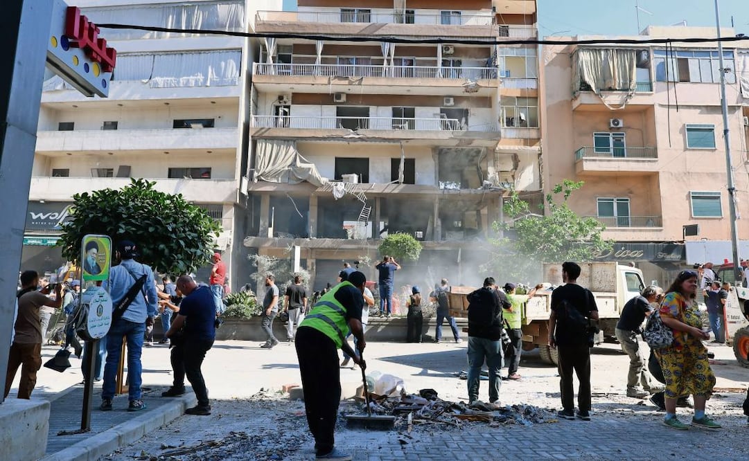 Libaneses limpian los escombros en el edificio impactado por un misil israelí, en un suburbio de Beirut. Foto: EFE