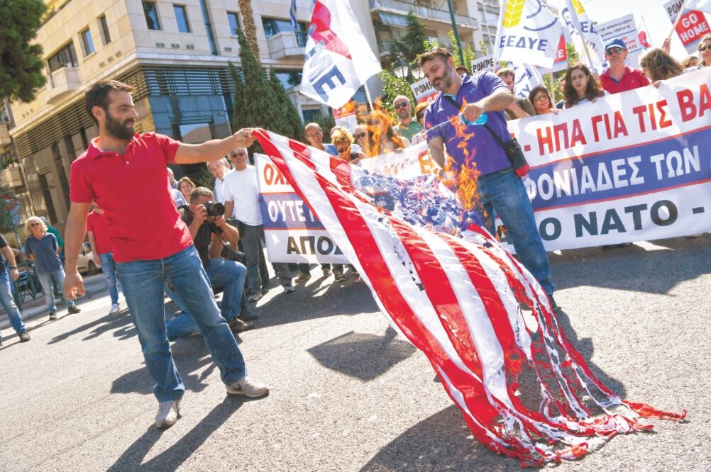 Griegos queman una bandera estadounidense durante una manifestación contra la visita del secretario de Estado, Mike Pompeo, en Atenas. Foto/MICHAEL VARAKLAS. AP