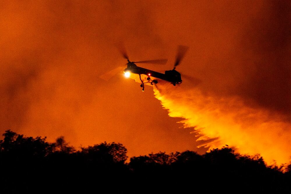 Un helicóptero arroja agua sobre el incendio Palisades en Mandeville Canyon, el sábado 11 de enero de 2025, en Los Ángeles. Foto: AP