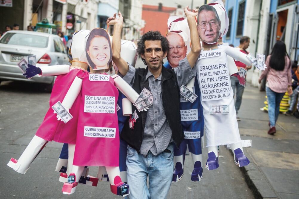 Un peruano carga en Lima piñatas representando a las figuras políticas que fueron noticia en 2017, incluyendo el ex presidente Alberto Fujimori (derecha). (ERNESTO BENAVIDES. AFP)