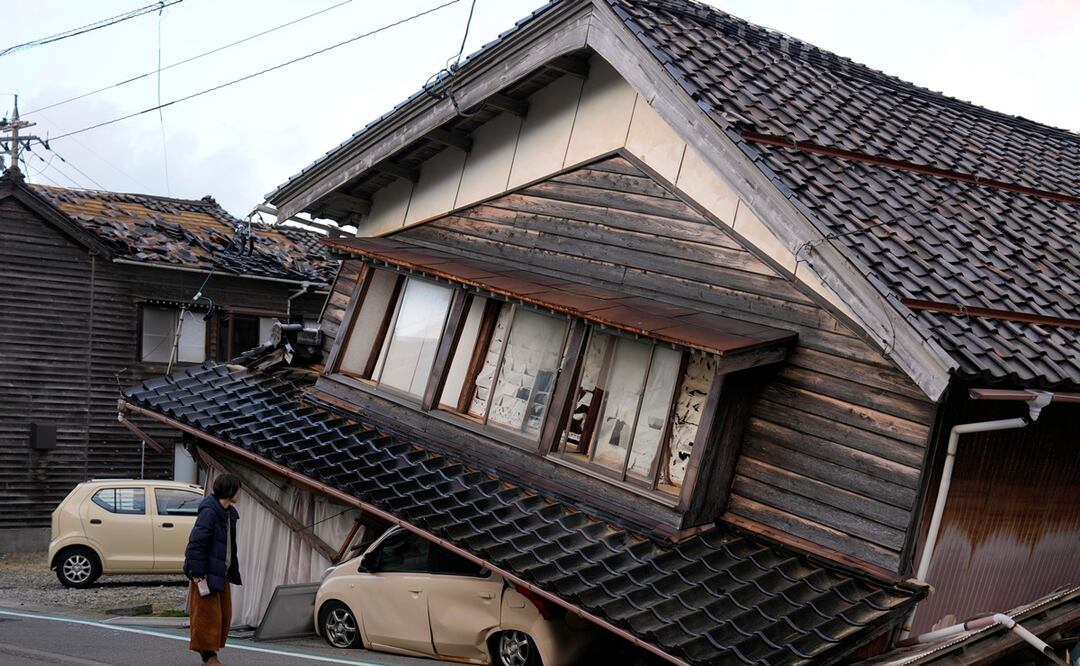 Una mujer observa una vivienda y vehículos dañados tras un fuerte terremoto en Tohi Town, en la península de Noto, Japón. Foto: EFE